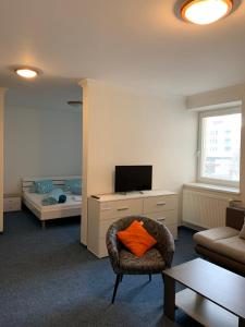ein Wohnzimmer mit einem Stuhl und einem orangenen Kissen in der Unterkunft Hotel TATRA in Malacky