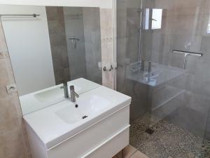 La salle de bains blanche est pourvue d'un lavabo et d'une douche. dans l'établissement Lieblingshaus, à Portiragnes