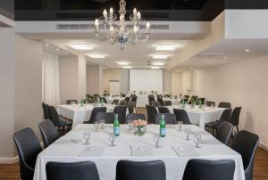 une salle de conférence avec des tables et des chaises blanches et un lustre dans l'établissement Island Luxurious Suites Hotel and Spa- By Saida Hotels, à Netanya