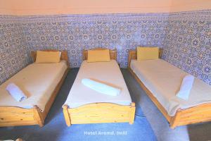 two twin beds in a room with a wall at Hotel Aremd - Aroumd Imlil route du Toubkal in Imlil