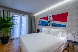 ein Schlafzimmer mit einem weißen Bett und einem Gemälde an der Wand in der Unterkunft Platforma Design Hotel in Tbilisi City