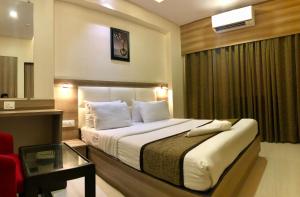 um quarto de hotel com uma cama grande e uma mesa em Hotel Avon Ruby Dadar em Mumbai