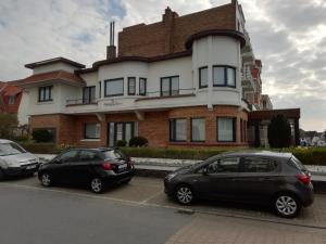 two cars parked in a parking lot in front of a building at LEHOUCK kamers ontbijt in Koksijde