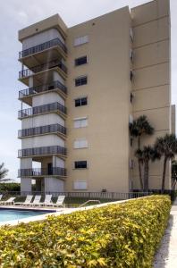 - un bâtiment avec une piscine et des palmiers dans l'établissement Jensen Beach Condo with Oceanfront Balcony and Pool!, à Jensen Beach