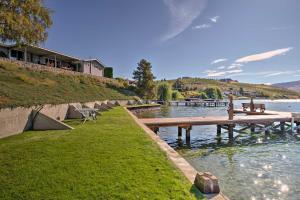 a dock on a body of water with a house at Waterfront Manson Cabin on Lake Chelan with Deck! in Manson