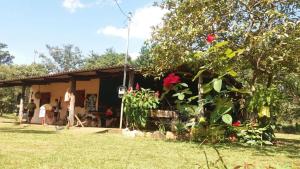 una pequeña casa con una flor roja delante de ella en Chalé Estância da Mata Nobres MT, en Nobres