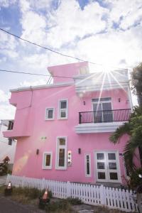 a pink house with a white fence in front of it at Love Summer B&B in Eluan