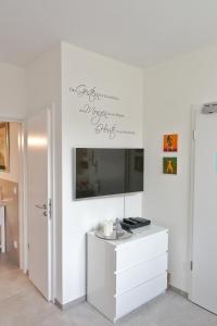 sala de estar con TV y pared blanca en La Petite Trier, en Trier