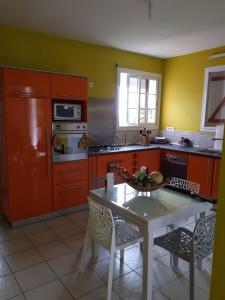 a kitchen with red cabinets and a table and a kitchen with a stove at Habitation du Château d'Ô - Vue sur Mer in Deshaies