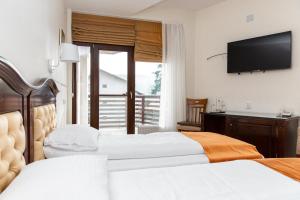 a hotel room with two beds and a flat screen tv at Pensiunea Favorit Ferice in Borsec