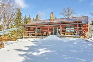 una cabaña de madera en invierno con nieve delante en Wonderful Home on Sand Lake with Expansive Porch!, en Squaw Lake