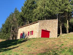 Saint-Apollinaire-de-RiasにあるLa bergerieの赤い扉が建つ石造りの建物