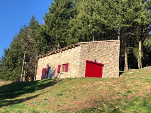 a stone building with red doors on a hill at La bergerie in Saint-Apollinaire-de-Rias