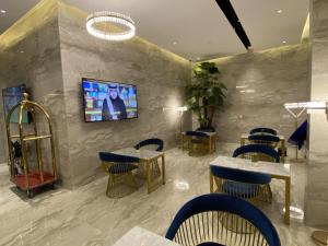 a restaurant with tables and chairs and a tv on a wall at Sadan Furnished Apartments in Riyadh