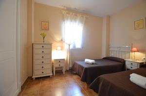 a bedroom with two beds and a dresser and a window at Apartamentos Solmares in Isla Canela