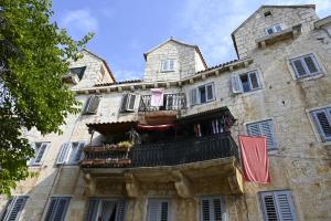 an old stone building with a balcony and clothes hanging from it at Apartments "sea view" Miki & Ivana in Bol