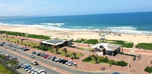 a beach with a building and a parking lot with cars at 904 Tenbury Beach Apartment in Durban