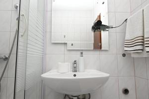 a white bathroom with a sink and a mirror at Apartments "sea view" Miki & Ivana in Bol +23 photos