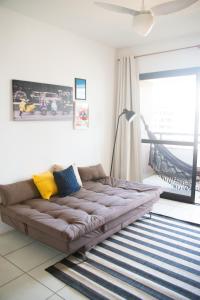 un gran sofá marrón en una sala de estar con ventana en Excelente apartamento no charmoso bairro do Rio Vermelho!, en Salvador