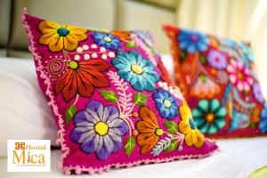 a pink pillow with colorful flowers on a bed at Hostal Mica in Abancay