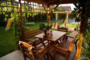 a wooden table and chairs sitting under a wooden pergola at La Villa Pergola in Szentgotthárd