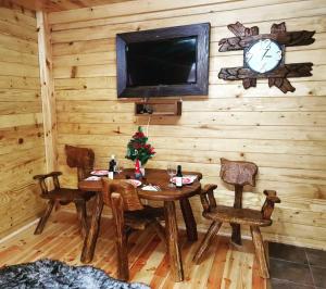 a dining room with a table and chairs and a clock at Brvnare Tomovic in Kolašin