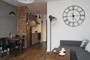 ein Wohnzimmer mit einem Sofa und einer Uhr an der Wand in der Unterkunft Schindler’s Factory Zabłocie Deluxe Apartments WAWELOFTS in Krakau