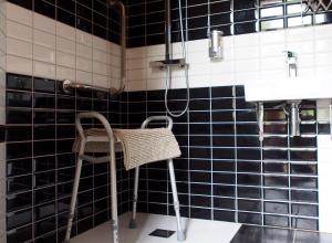 a bathroom with black tiles and a chair and a shower at Hôtel spa Transhumance & cie in Bedous