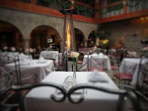 una habitación llena de mesas con manteles blancos con un jarrón con una flor en Hotel San Francisco Plaza, en Cusco