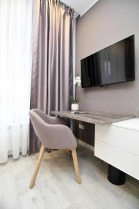 a desk with a chair and a television on a wall at PLATINUM ROOMS butique hotel in Sarajevo