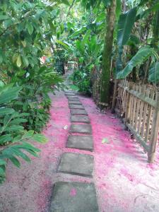 una pasarela cubierta de plantas rosas junto a una valla en Barra Quintal Apto 04, en Barra Grande