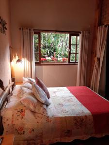 a bedroom with a large bed with a window at Chale Raio De Luz in Visconde De Maua