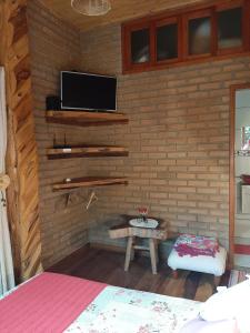 a room with a tv on a brick wall at Chale Raio De Luz in Visconde De Maua