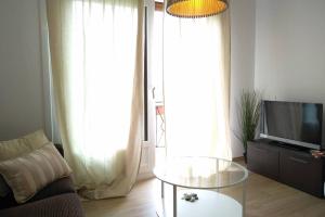 ein Wohnzimmer mit einem TV und einem Glastisch in der Unterkunft Apartamento Teresa in Pontevedra