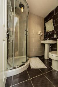 uma casa de banho com um chuveiro, um WC e um lavatório. em Dockside Hotel em Londres
