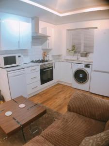 a kitchen with white appliances and a table and a couch at Comfortable double bedroom lovely bungalow in Manchester