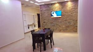 a black table and chairs in a room with a brick wall at Appartement Plage Mehdia pour famille in Mehdiya-Plage
