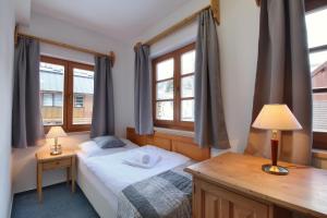 a small bedroom with a bed and two windows at Hotel Hvezda in Pec pod Sněžkou