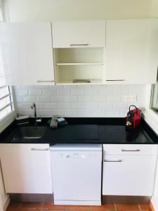 une cuisine avec des placards blancs et un comptoir noir dans l'établissement Appartement Anchorage Anse des rochers, à Saint-François
