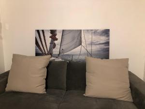 a couch with two pillows and a picture of a sailboat at Be On The Beach in Sainte-Anne