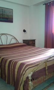ein Schlafzimmer mit einem Bett mit einer gestreiften Decke in der Unterkunft Departamento Centro Villa Carlos Paz in Villa Carlos Paz