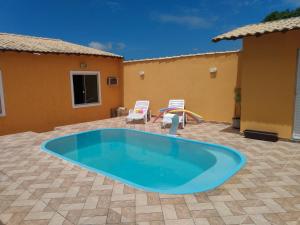 a large blue pool in a patio with two chairs at Orange House in Araruama