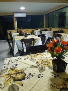 a dining room with tables and chairs with flowers on them at Pousada Gamela do Maragogi in Maragogi