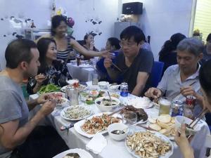 Un groupe de personnes assises autour d'une table et mangeant de la nourriture dans l'établissement Saigonnais Homestay (Maison de Tran Le), à Hô-Chi-Minh-Ville