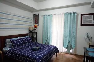 a bedroom with a blue plaid bed and a window at Comfy condo unit 5mins from Mactan Airport+Netflix in Mactan