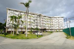 a large white building with palm trees and a street at Comfy condo unit 5mins from Mactan Airport+Netflix in Mactan