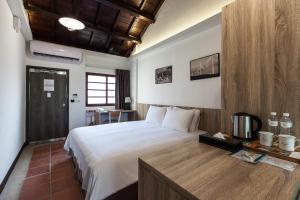 馬公市的住宿－貝富門旅館 - 澎湖灣行旅，卧室配有一张白色大床和一张书桌