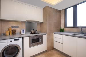 a kitchen with white cabinets and a washer and dryer at Somerset Grandview Shenzhen in Shenzhen