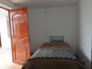 a small bedroom with a bed and a door at Casa ValPer in Cusco