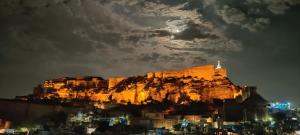 une montagne éclairée la nuit avec une ville dans l'établissement Castle View Heritage Haveli, à Jodhpur
